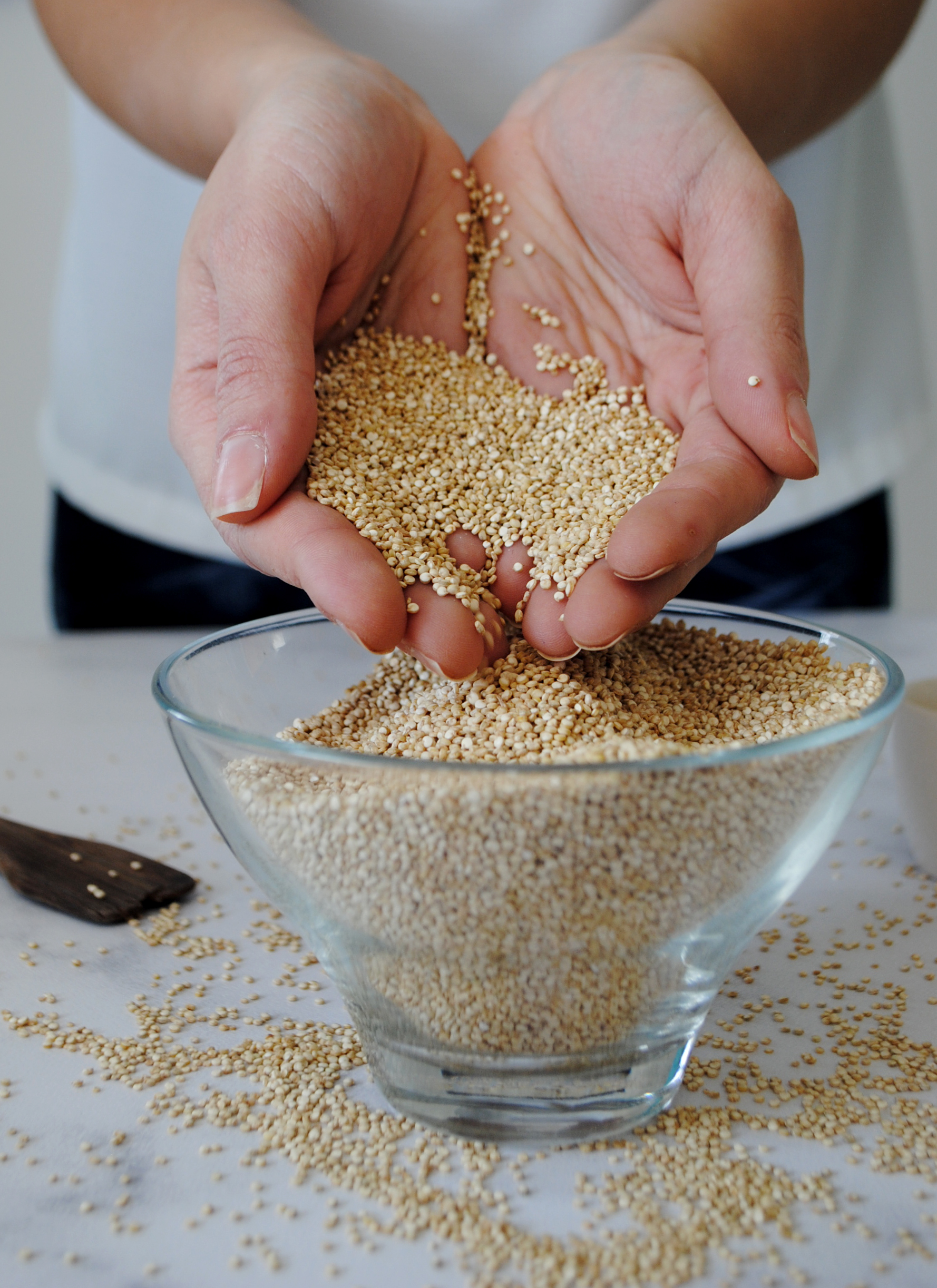 Quinoa held in cupped hands over a full bowl of quinoa