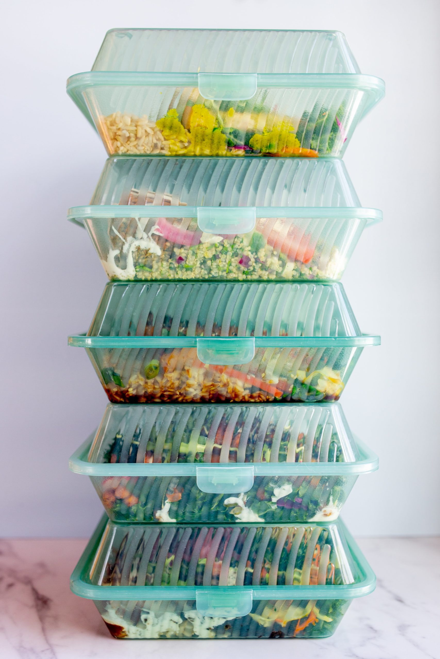 five prepared meals stacked in reusable containers