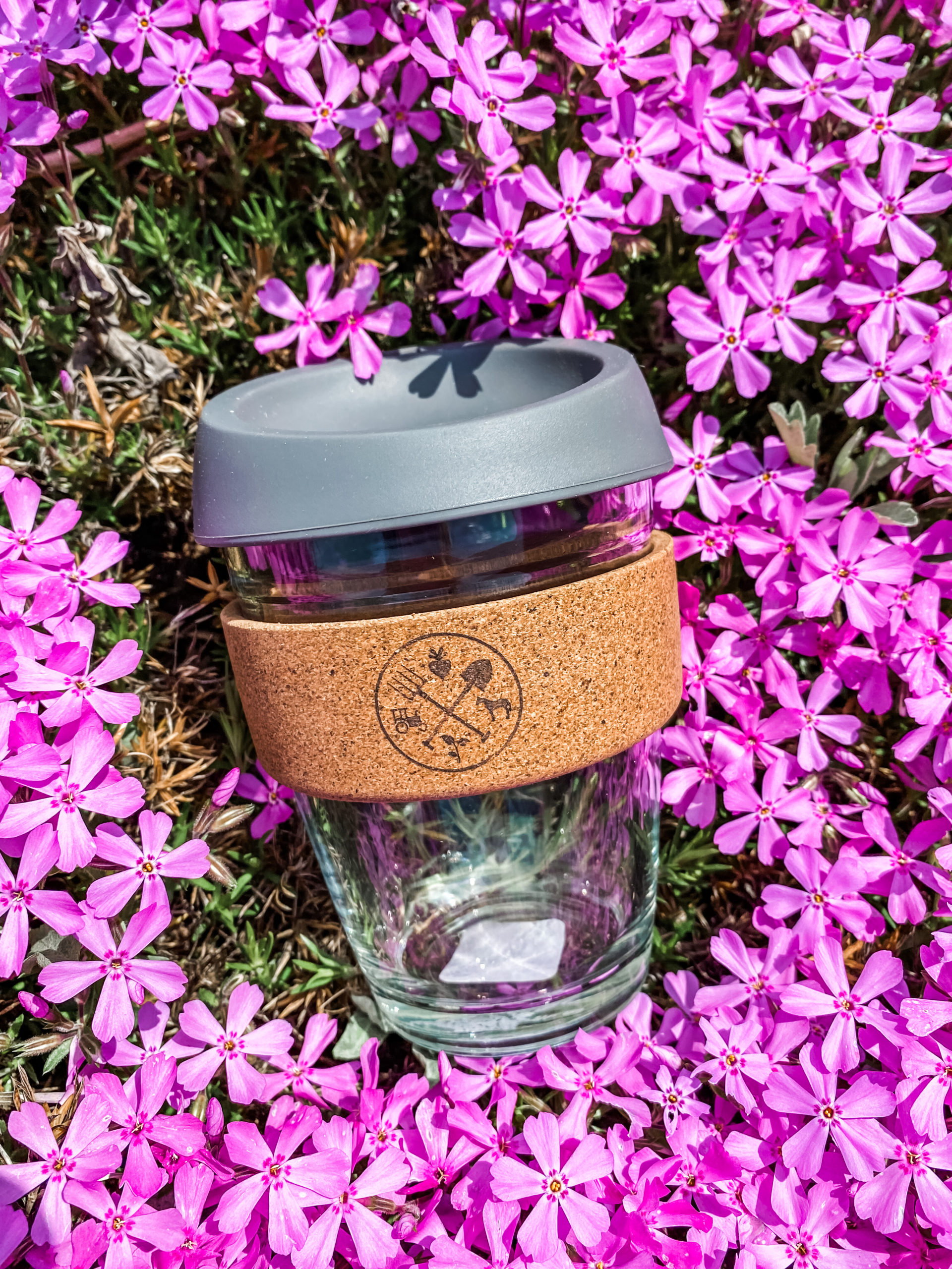 reusable coffee cup laying a bed of purple flowers